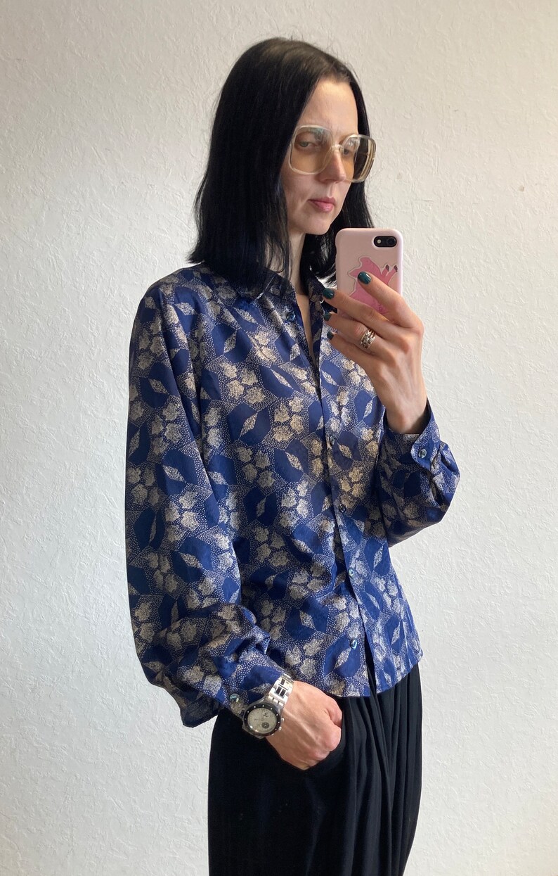 Pu&ograve; includere: Una camicia a maniche lunghe blu e oro con motivo, chiusura con bottoni e vestibilit&agrave; rilassata.
