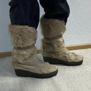 Könnte beinhalten: Ein Paar braune Winterstiefel aus Kunstfell mit dicker Sohle.
