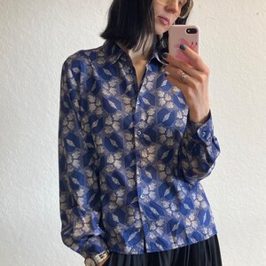 Pu&ograve; includere: Una camicia a maniche lunghe con bottoni e colletto blu e bianco con motivo. La camicia &egrave; realizzata in un materiale setoso e ha una vestibilit&agrave; rilassata.