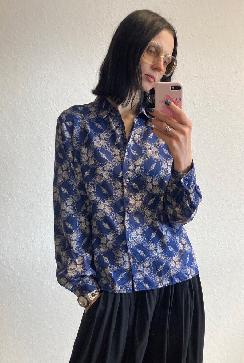 Pu&ograve; includere: Una camicia a maniche lunghe con bottoni e colletto blu e bianco con motivo. La camicia &egrave; realizzata in un materiale setoso e ha una vestibilit&agrave; rilassata.