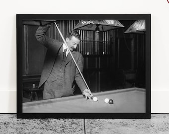 May include: A black and white photograph of a man playing snooker. He is wearing a suit and tie and is holding a snooker cue. The snooker table is green and there are two white balls on the table.