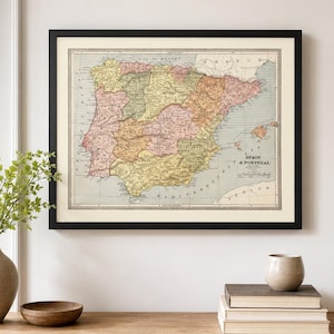 May include: A framed vintage-style map of Spain and Portugal featuring muted pastel colors, detailed geographical borders, and clear black text labels. The map is enclosed in a simple black frame with a cream-colored mat, displaying the Iberian Peninsula.