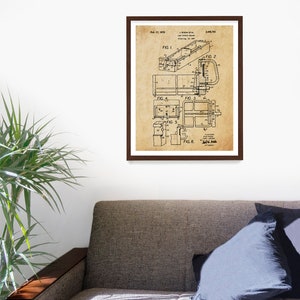 May include: A framed vintage patent print featuring technical drawings of a device. The print has a sepia tone and is encased in a dark brown frame. The drawings include various figures and labels, with the date Feb. 17, 1970 visible.