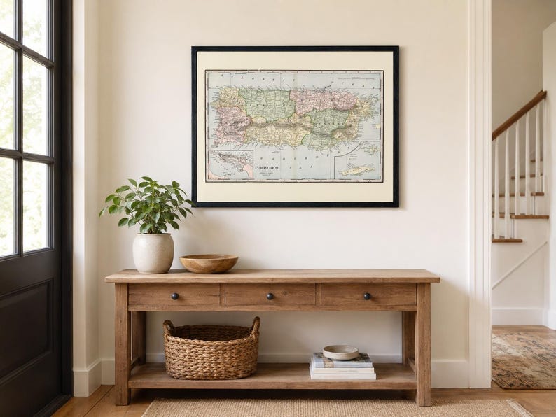 K&ouml;nnte beinhalten: Eine gerahmte historische Karte von Porto Rico mit dezenten, farblich gekennzeichneten Regionen, detaillierter Topografie und K&uuml;stenlinien. Die Karte befindet sich in einem d&uuml;nnen schwarzen Rahmen mit cremefarbenem Passepartout und zeigt deutliche kartografische Beschriftungen.