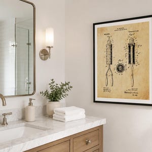 May include: A framed wall art print featuring a vintage patent illustration of a curling iron on aged, tan-coloured paper. The black ink technical drawing displays three distinct views of the device labelled Fig 1, Fig 2, and Fig 3 with text.