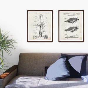 May include: Two black and white vintage patent drawings in brown frames. The left drawing shows a windmill design. The right drawing shows a solar panel design. The drawings are on a white wall above a brown couch.
