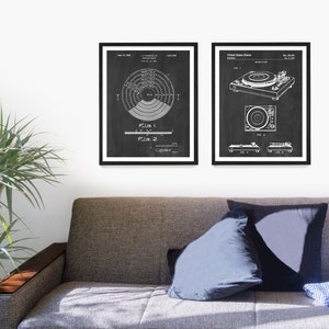 May include: Two black and white vintage patent drawings of a record player. The first drawing shows a diagram of a record player turntable. The second drawing shows a side view of a record player. The drawings are framed in black frames and are hanging on a white wall.