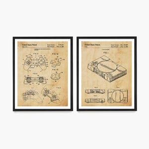 Peut inclure: Deux impressions encadr&eacute;es noires de dessins de brevets vintage pour une console de jeu vid&eacute;o et une manette. Le dessin de la console est intitul&eacute; "FIG. I" et le dessin de la manette est intitul&eacute; "FIG. 12".