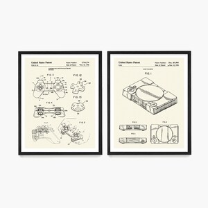 Peut inclure: Deux tirages encadr&eacute;s noirs de dessins de brevets vintage pour une console de jeu vid&eacute;o et une manette. Le dessin de brevet de la console montre une vue de dessus de la console avec le texte "FIG. 1" et le dessin de brevet de la manette montre une vue de c&ocirc;t&eacute; de la manette avec le texte "FIG. 3".