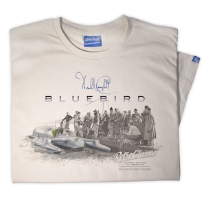 Puede incluir: Una camiseta beige con una ilustración en blanco y negro de una embarcación llamada Bluebird. La ilustración muestra la embarcación en el agua con un grupo de personas de pie en un muelle. La camiseta también presenta la firma de Donald Campbell y el texto "Retro Classic Campbell Heritage Collaboration 1957 Water Speed Record".