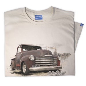 May include: A white t-shirt featuring a vintage-style illustration of a rusty red pickup truck. The truck has a number plate that reads "RC 1948". The image is set against a faded, sandy background with the text "Retro Classic" printed at the bottom.
