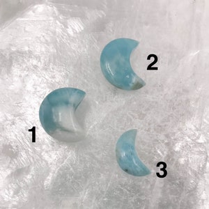 May include: Three blue and white crescent moon shaped stones. The stones are numbered 1, 2, and 3.