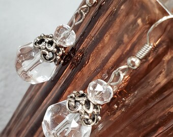 Puede incluir: Un par de pendientes de plata con cuentas de cristal transparente y detalles de plata ornamentados.