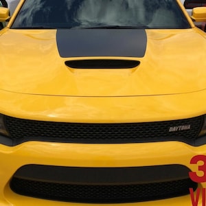 May include: A bright yellow car with a black hood stripe and a black grille. The word "DAYTONA" is visible on the grille. The image also displays the text "3M VINYL".