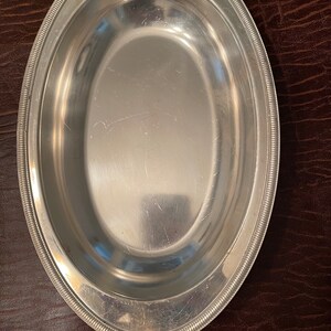May include: A silver oval serving dish with a beaded rim.