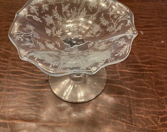 May include: A clear glass pedestal bowl with a scalloped edge and a floral etched design.