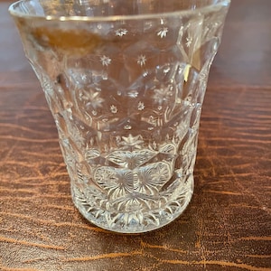 Puede incluir: Un vaso de chupito de vidrio transparente con un diseño de vidrio cortado. El vaso tiene un patrón de estrella.