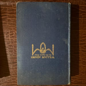 Może przedstawiać: Granatowa okładka książki ze złotymi literami i ozdobnym emblematem. Tekst brzmi "WILLIAM ADAMS" i "The Old English Potter". Książka jest umieszczona na brązowym, teksturowanym tle.