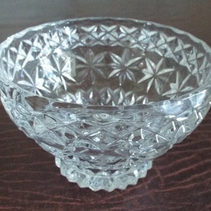 May include: A clear glass bowl with a cut glass design. The bowl has a wide, round base and a flared rim.