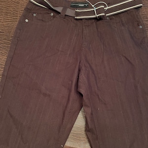 May include: Brown shorts with a white and grey striped belt. The shorts have a front pocket and a back pocket.