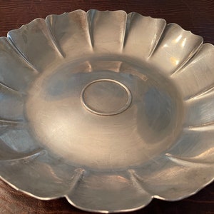 May include: A silver serving dish with a scalloped edge and a smooth, reflective surface.