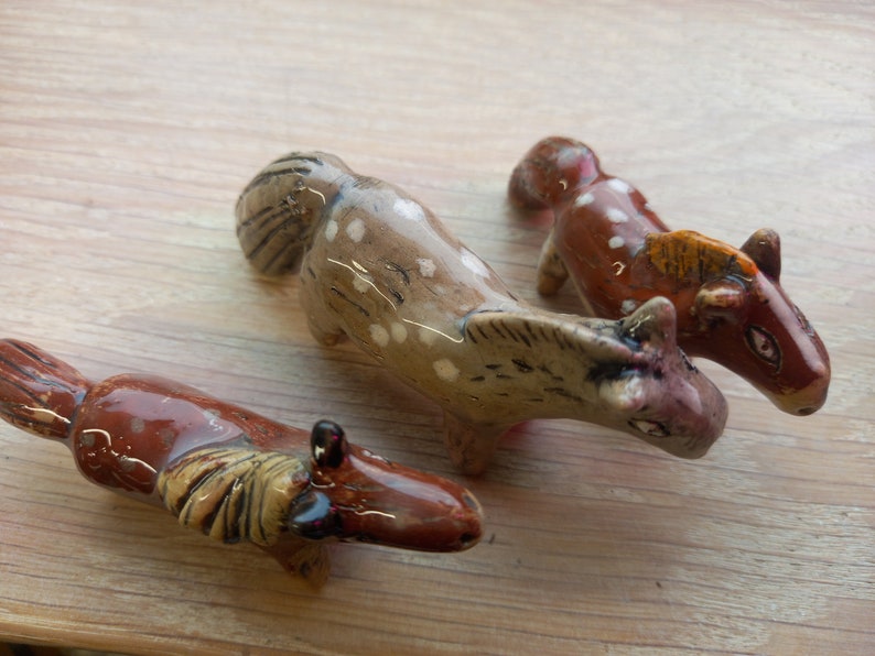 Puede incluir: Tres figuritas de caballos de cer&aacute;mica. Una es marr&oacute;n con manchas blancas, otra es marr&oacute;n con manchas blancas y una crin marr&oacute;n claro, y la &uacute;ltima es marr&oacute;n claro con manchas blancas y una crin marr&oacute;n claro.