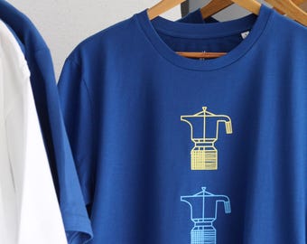 Könnte beinhalten: Ein königsblaues T-Shirt mit kurzen Ärmeln und zwei übereinander angeordneten Grafikdrucken von Mokkakannen. Die obere Kanne ist gelb dargestellt, die untere hellblau. Das T-Shirt hängt an einem Holzkleiderbügel.