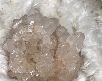 Op de afbeelding: Een cluster van heldere, doorschijnende kwartskristallen met een lichtbruine tint. De kristallen zijn in een natuurlijke formatie geclusterd, waardoor een unieke en interessante vorm ontstaat.