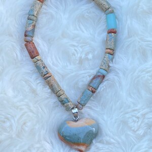 May include: A necklace made of brown, blue, and white patterned beads with a heart-shaped pendant made of the same patterned stone.