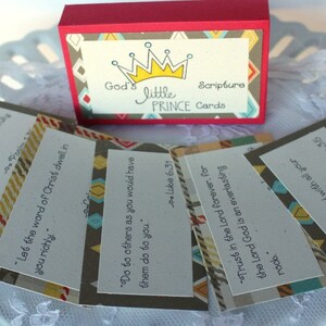 Puede incluir: Un juego de peque&ntilde;as tarjetas con citas b&iacute;blicas inspiradoras impresas en ellas. Las tarjetas est&aacute;n decoradas con un patr&oacute;n geom&eacute;trico en tonos marrones, azules y amarillos. Las tarjetas est&aacute;n empaquetadas en una peque&ntilde;a caja con una tapa roja y un patr&oacute;n geom&eacute;trico en la parte delantera. La caja tiene las palabras "God's Little Prince Cards" impresas en ella.