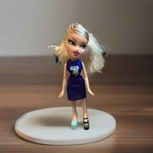 Puede incluir: Muñeca Bratz con cabello rubio y un vestido azul oscuro con el número 7. La muñeca lleva un zapato azul claro y otro negro. Está sobre una plataforma circular blanca.
