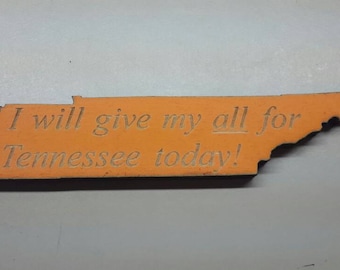 Op de afbeelding: Oranje houten uitsnede van de staat Tennessee met de tekst "I will give my all for Tennessee today!"