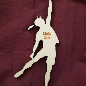 May include: Wooden ornament of a person in a dance pose with the name "Molly 2019" engraved on the front.
