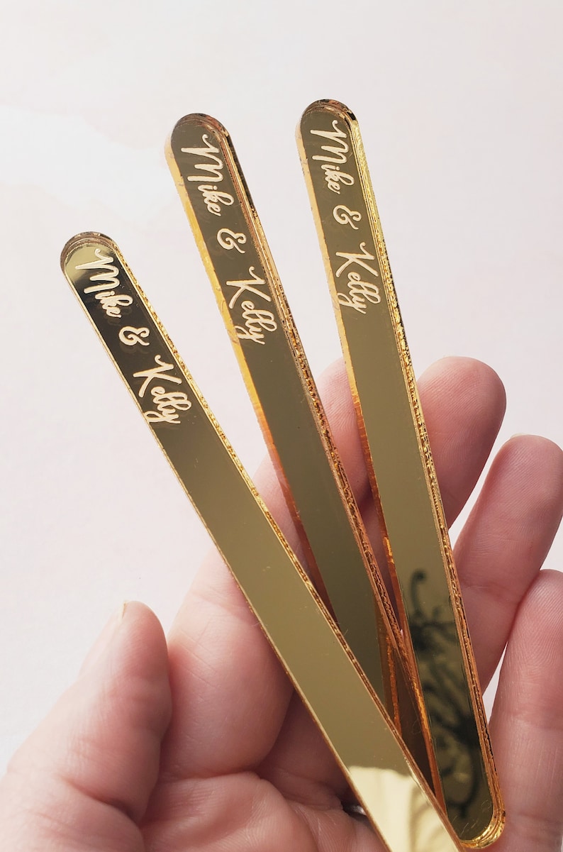 May include: Three gold-colored acrylic sticks with the text "Mike & Kelly" engraved on each.