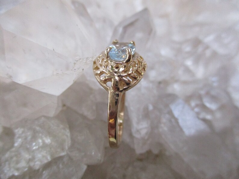 May include: A gold ring with a delicate filigree design and a light blue gemstone.