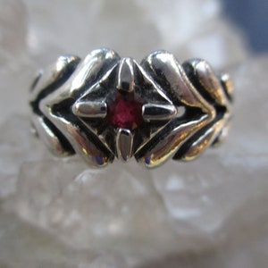 Puede incluir: Un anillo de plata con una piedra preciosa roja engastada en un diseño geométrico.