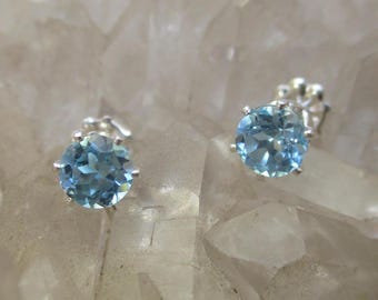 May include: A pair of silver earrings with light blue round gemstones. The earrings have a simple design and are perfect for everyday wear.