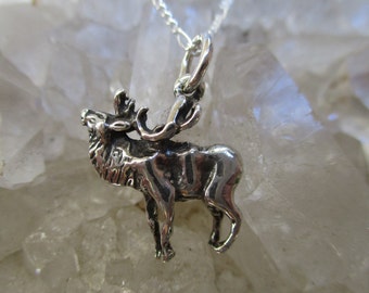 May include: A silver elk pendant charm with a detailed design. The pendant is hanging from a silver chain.