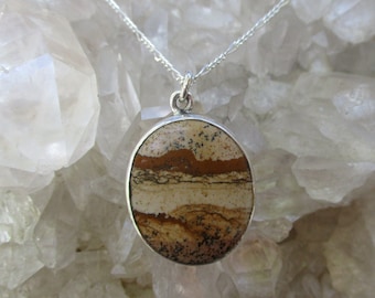 May include: A silver chain necklace with a brown, white, and black oval pendant made of banded agate.