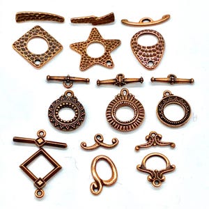 May include: A collection of 15 copper-toned metal jewelry findings, including toggle clasps, star charms, and decorative loops. These findings are perfect for adding a touch of rustic elegance to your jewelry designs.