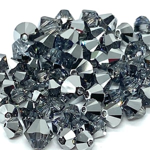 May include: A large pile of silver-toned crystal beads with a faceted design. The beads have a hole in the center for stringing.
