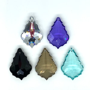Op de afbeelding: Vijf kristallen druppelhangers in verschillende kleuren, waaronder helder, zwart, paars, bruin en blauw.