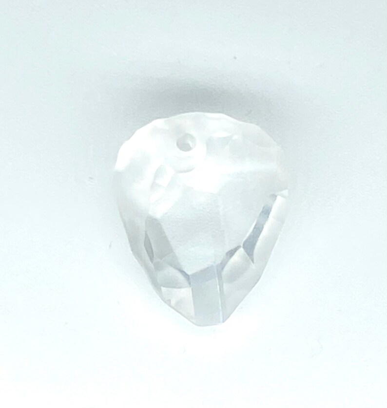 May include: A clear glass crystal bead with a faceted design and a hole in the centre for stringing.