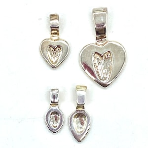 May include: Four silver-toned metal pendant bails, two heart-shaped and two teardrop-shaped.
