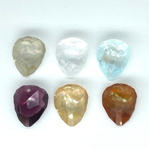 May include: Six faceted teardrop-shaped crystal beads in various colours: clear, white, light blue, purple, yellow, and orange.