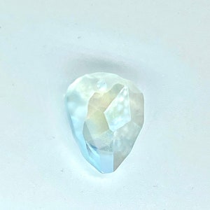 May include: A clear, faceted, teardrop-shaped gemstone with a light blue hue.
