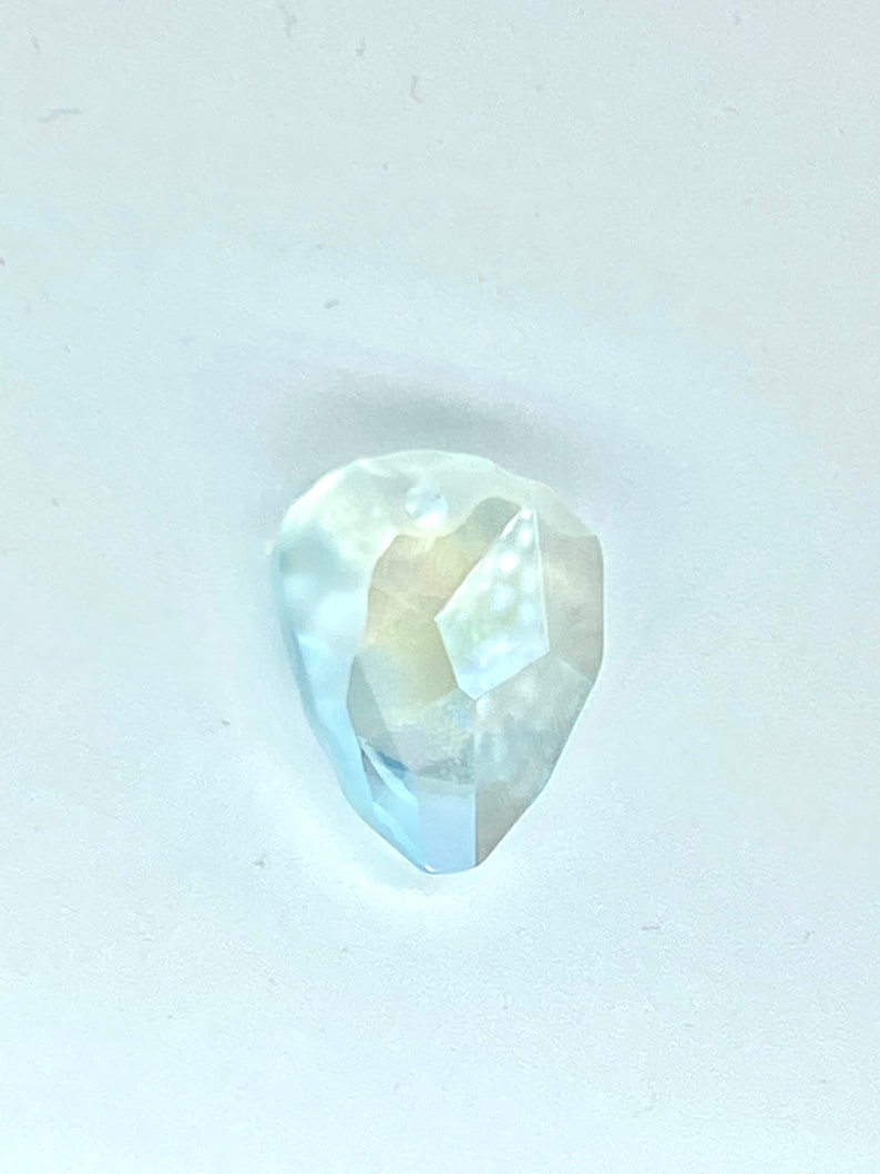 May include: A clear, faceted, teardrop-shaped gemstone with a light blue hue.