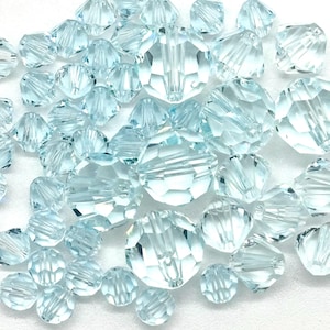 May include: A collection of light blue faceted glass beads. The beads are round and have a slightly elongated shape. They are perfect for jewelry making or other craft projects.