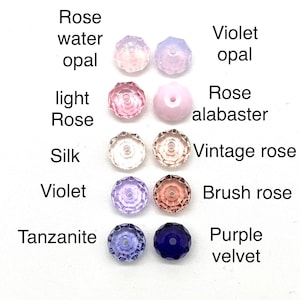 May include: Assortment of 10 round glass beads in various shades of pink, purple, and blue. The beads are labeled with names like "Rose water opal", "Violet opal", "Light Rose", "Rose alabaster", "Silk", "Vintage rose", "Violet", "Brush rose", "Tanzanite", and "Purple velvet".