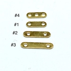 May include: Four gold-colored metal connector pieces with two holes each. The pieces are labeled #1, #2, #3, and #4, with #4 being the largest and #1 being the smallest.
